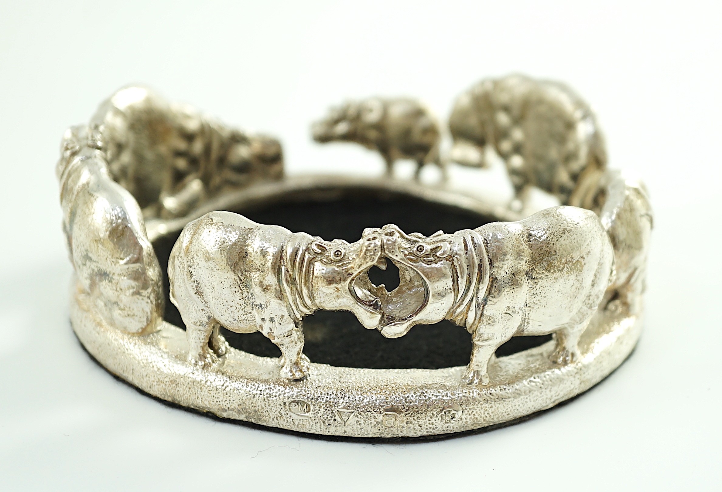 Patrick Mavros - A modern novelty silver bottle coaster, modelled as a continuous bloat of hippopotami, in various positions